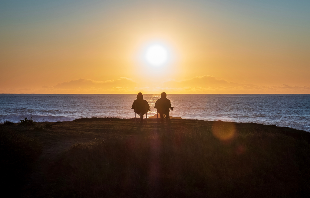 two silhouettes in front of a sunset