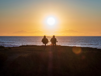 two silhouettes in front of a sunset