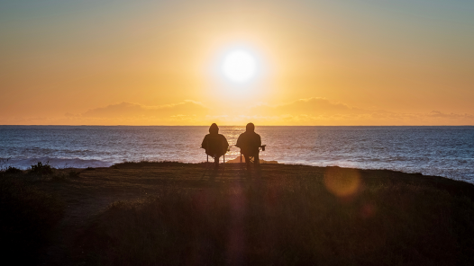 two silhouettes in front of a sunset